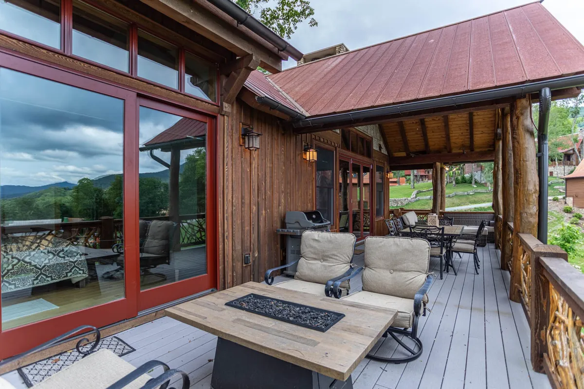 A spacious wooden deck equipped with a fire pit table, comfortable seating, and panoramic mountain views. The setup is perfect for outdoor gatherings, storytelling by the fire, or simply soaking in the vistas, seamlessly connecting indoor and outdoor social spaces.