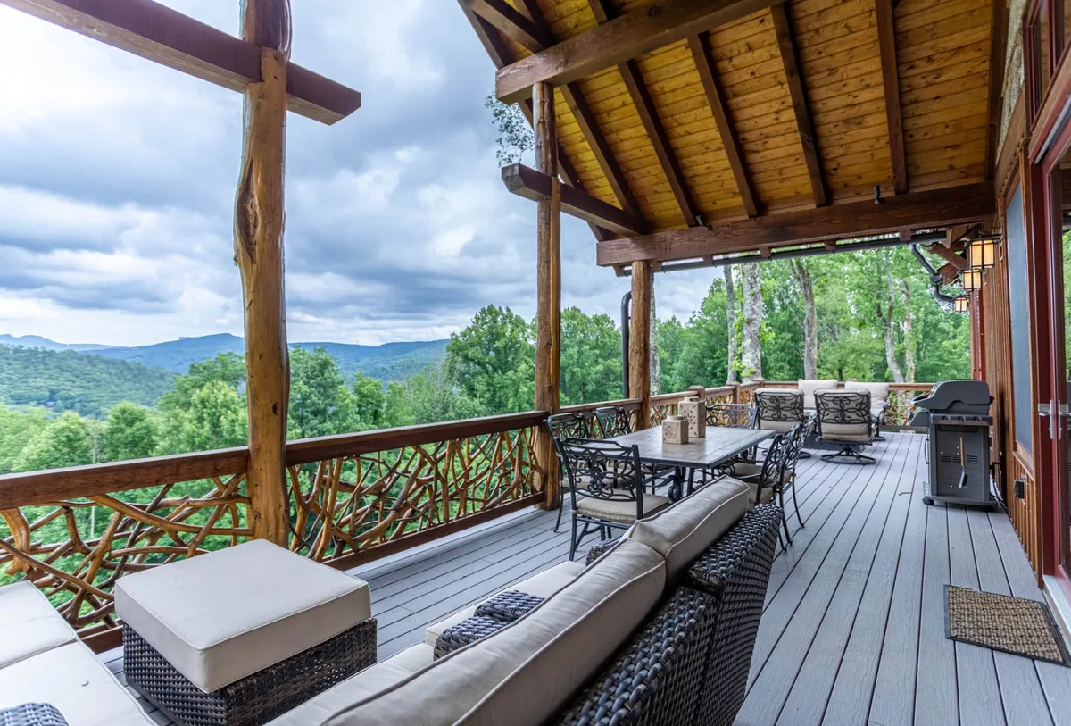 A spacious deck featuring outdoor furniture, wooden railings, and a sweeping view of the mountains. The space is set up for outdoor dining or lounging, with ample seating and a peaceful ambiance for group meals or wine tasting while soaking in the scenery.