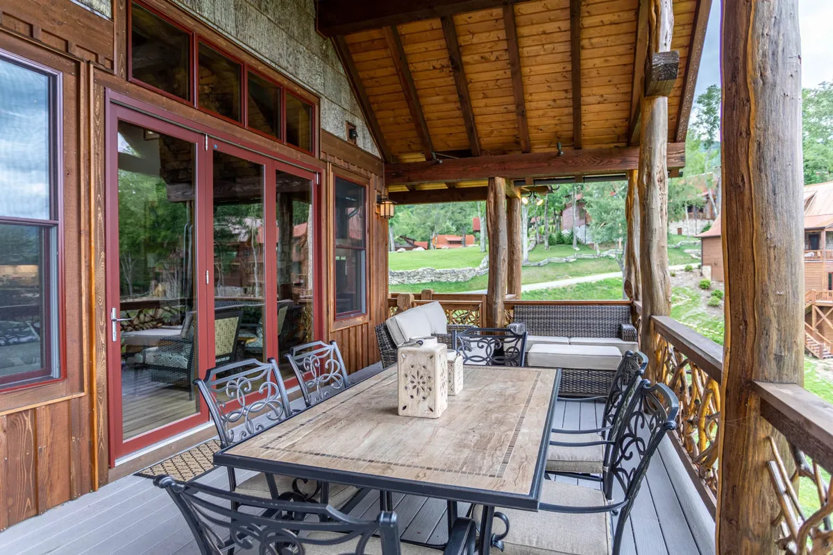 A wooden outdoor dining table with comfortable seating sits on a landscaped patio, overlooking serene natural surroundings. Decorative lanterns add warmth, and the view hints at relaxing moments in nature, perfect for group gatherings or meals al fresco.
